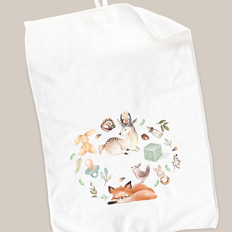 Biała ręcznik z kolorowym nadrukiem przedstawiającym leżącego lisa, jelenia, zająca oraz inne leśne motywy i zabawki dziecięce, tworzących okrągły wzór.