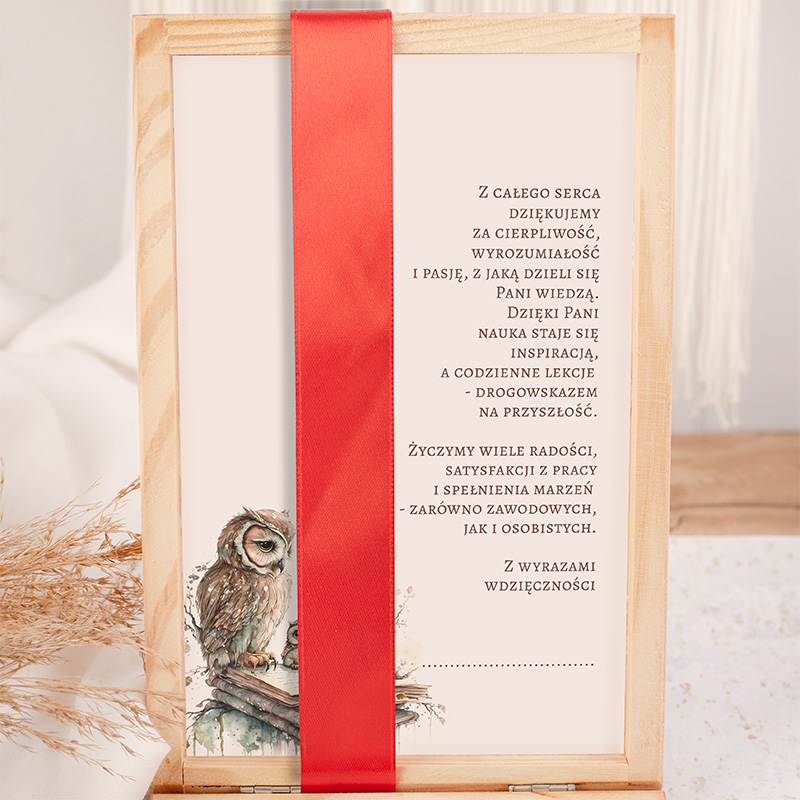 Kartka z podziękowaniami umieszczona w drewnianej ramie z czerwoną wstążką. Na tle znajduje się ilustracja sowy na książce oraz tekst wyrażający wdzięczność za naukę i inspirację. Całość w jasnych tonacjach z eleganckim wykończeniem.