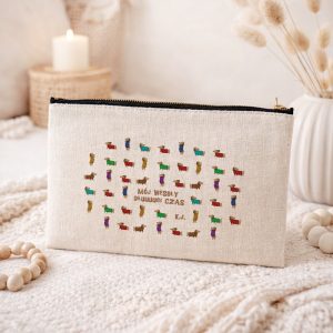 Kosmetyczka w naturalnym kolorze z haftem przedstawiającym kolorowe kamienie i napisem "MÓJ WESOŁY ODŁUGUJĄCY CZAS".