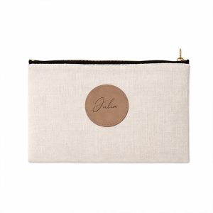 Zamek błyskawiczny torby w kolorze beżowym z okrągłą, brązową metką z imieniem "Julia".