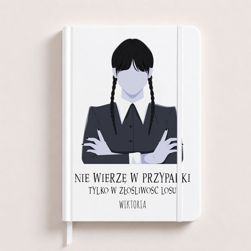 Biały notes z grafikom postaci w czarnym stroju, z długimi warkoczami i napisem "NIE WIERZĘ W PRZYPADKI TYLKO W ZŁOŚLIWOŚĆ LOSU".