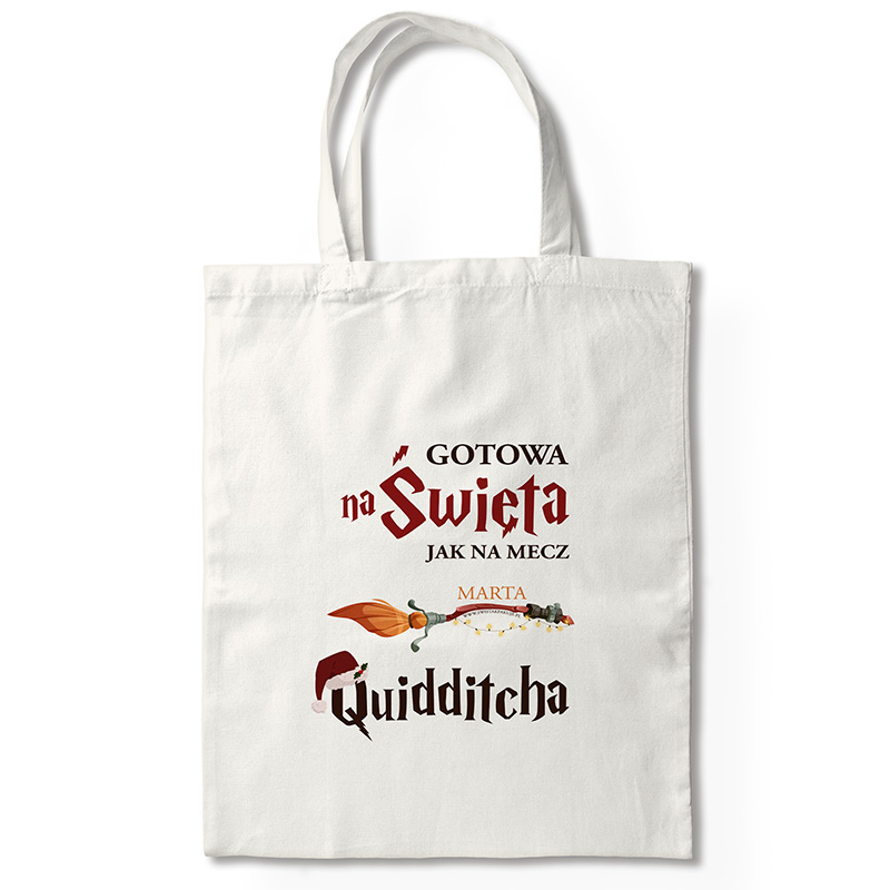Biała torba z nadrukiem w stylu fantasy, na którym widnieje tekst: "GOTOWA na Święta JAK NA MECZ MARTA Quidditcha", z ilustracją miotły i świątecznymi dodatkami.