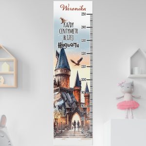 Dziecięca miarka wzrostu na ścianie, przedstawiająca zamek z wysokimi wieżami, otoczony przez otwarte niebo i wylatującego ptaka, z napisem "Każdy centymetr bliżej Hogwartu" oraz imieniem "Weronika", z podziałką wzrostu do 150 cm.
