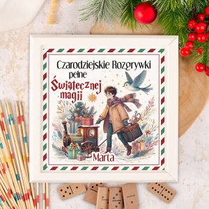Ilustracja o tematyce świątecznej przedstawiająca młodego chłopca z torbą i wózkiem, w którym znajduje się mała lokomotywa oraz prezenty. W tle widać choinkę i lecącego ptaka. Tytuł książki "Czarodziejskie Rozgrywki pełne Świątecznej magii" znajduje się na górze ilustracji. Całość otoczona jest dekoracyjną ramką.