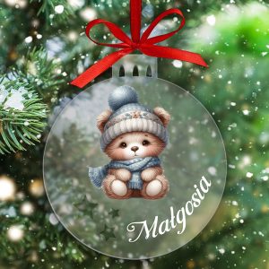 Szklana bombka świąteczna przedstawiająca urocze misie w zimowym nakryciu, zawieszona na choince, z napisem "Małgosia" oraz tłem pełnym zielonych gałęzi i padającego śniegu.