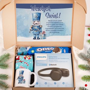 Otwarte pudełko prezentowe z niebieską kartką z postacią żołnierza świątecznego oraz napisem 'Wesołych Świąt!'. Wewnątrz znajdują się: paczka ciastek Oreo, słuchawki Philips, kolorowy kubek oraz otulacz. Tło z gałązkami świątecznymi.