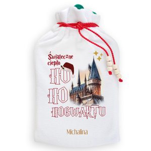 Biały worek na prezenty z grafiką zamku, z napisem 'Świąteczne ciepło HO HO HOGWARTU' oraz elementami bożonarodzeniowymi, takimi jak czapka Mikołaja. Worek ozdobiony czerwoną sznurkiem i koralikami.