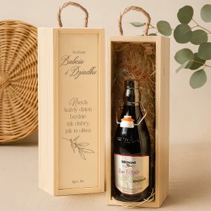 Drewniane pudełko z napisem "Kochani Babciu i Dziadku" oraz życzeniem nawiązującym do oliwy, zawierające butelkę oliwy Monini, stojące na neutralnym tle.