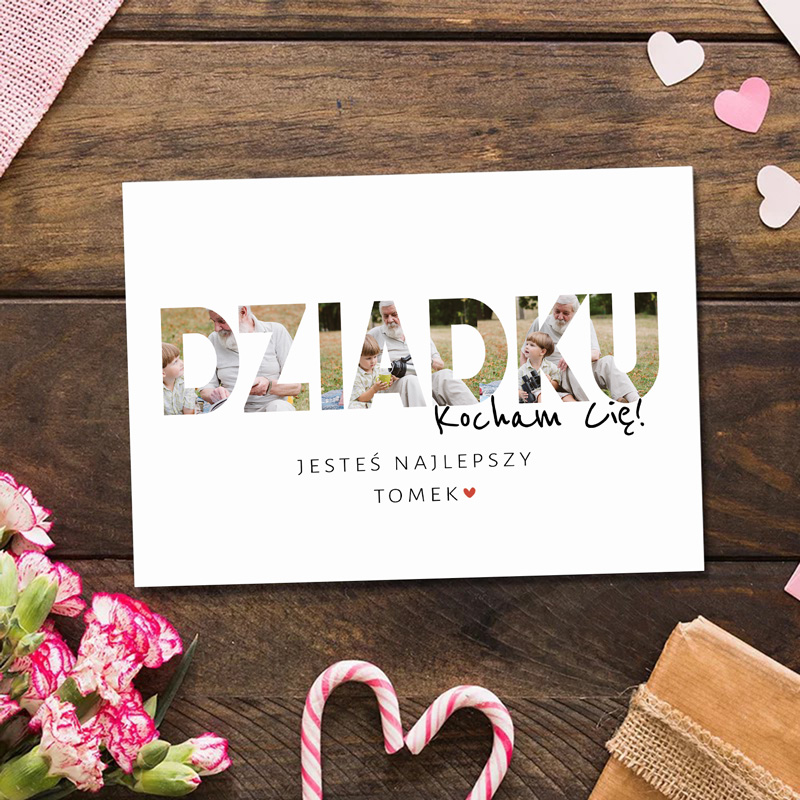 Kartka z napisem 'DZIADKU Kocham Cię!' z wyciętymi zdjęciami, tekst pod spodem brzmi 'Jesteś najlepszy Tomek'. Tło z drewnianych desek i dekoracje w postaci serduszek oraz kwiatów.