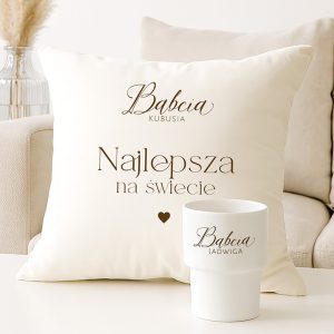 Na jasnej poduszce z napisem 'Najlepsza na świecie' znajduje się także imię 'Babcia Kubuś'. Obok stoi biały kubek z napisem 'Babcia Jadwiga'.