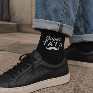 skarepty-na-dzien-taty-super-tata Czarne skarpetki z napisem "Super Tata" i białą muszką, noszone z dżinsami i czarnymi sneakersami.