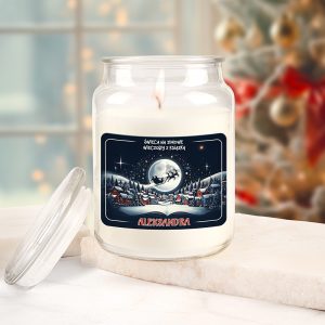 Szklany słoik z zapaloną świecą, na etykiecie znajdują się napisy "ŚWIECA NA ZIMOWE WIECZORY Z KSIĄŻKĄ" oraz imię "ALEKSANDRA", w tle widać dekorowane świątecznie drzewo.