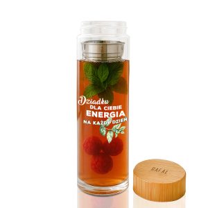 Przezroczysta butelka z herbatą, w której unoszą się liście mięty oraz maliny, z widocznym napisem: 'Dziadku dla Ciebie energia na każdy dzień'. Obok pokrywka z drewna bambusowego ze słowem 'RAFAŁ'.