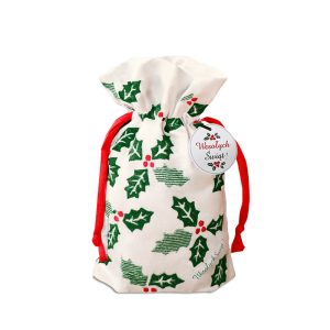 worek-na-butelke-z-okazji-swiat.jpg Mały woreczek świąteczny wykonany z białego materiału, ozdobiony zielonymi liśćmi ostrokrzewu i czerwonymi jagodami, z czerwonymi sznurkami do związania oraz okrągłą etykietą z napisem 'Wesołych Świąt!'.