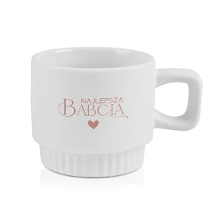 Biała filiżanka z napisem 'Najlepsza Babcia' w różowym kolorze, z serduszkiem poniżej napisu, na tle białym.