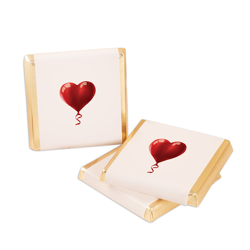Dwa opakowania czekoladek w kolorze kremowym z nadrukiem czerwonego balonika w kształcie serca, zdobione złotym brzegiem.