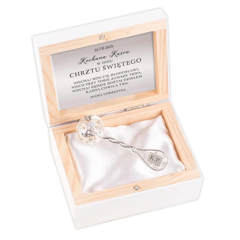 Srebrna łyżeczka z ozdobnym uchwytem, umieszczona w eleganckim drewnianym pudełku, wewnątrz którego znajduje się także dedykacja nawiązująca do chrztu dziecka.