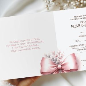 Elegancka zaproszenie na pierwszą komunię, z różową wstążką i kwiatowymi detalami. Tekst modlitwy i szczegóły uroczystości są w stylizowanej czcionce na białym tle, z jedną stroną wizualnie podkreśloną dekoracjami.