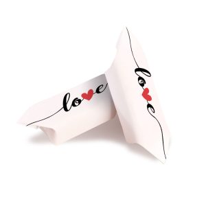 Dwie białe poduszki z napisem 'love' ozdobionym czerwonym sercem, ułożone obok siebie.