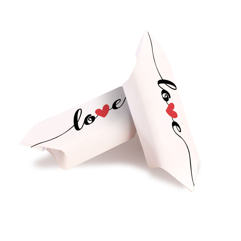 Dwie białe poduszki z napisem 'love' ozdobionym czerwonym sercem, ułożone obok siebie.