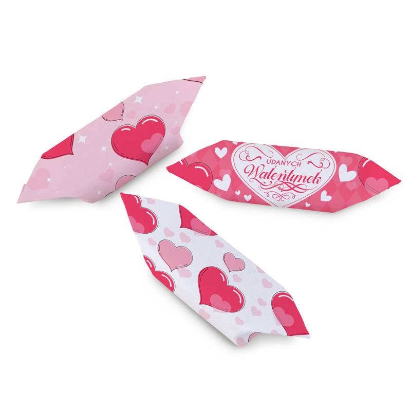 Trzy różowe łakocie w kształcie bryłek, dekorowane sercami i napisami, z motywem walentynkowym. Na jednym z nich widnieje napis 'Udanych Walentynek'.