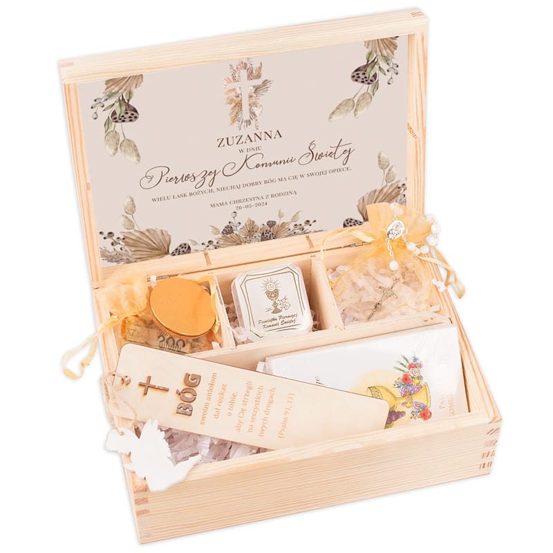 Skrzynka z prezentami na Pierwszą Komunię Świętą, zawierająca m.in. świecę, wosk dla ołtarza, kartki oraz ozdobny medalik, z napisem 'ZUZANNA w dniu Pierwszej Komunii Świętej' na wieczku.