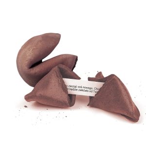 Rozłamany kokosowy fortune cookie, z widoczną wróżbą w języku polskim, na tle białym. Ocalały, nieuszkodzony połowa cookie wystaje z jednej strony.