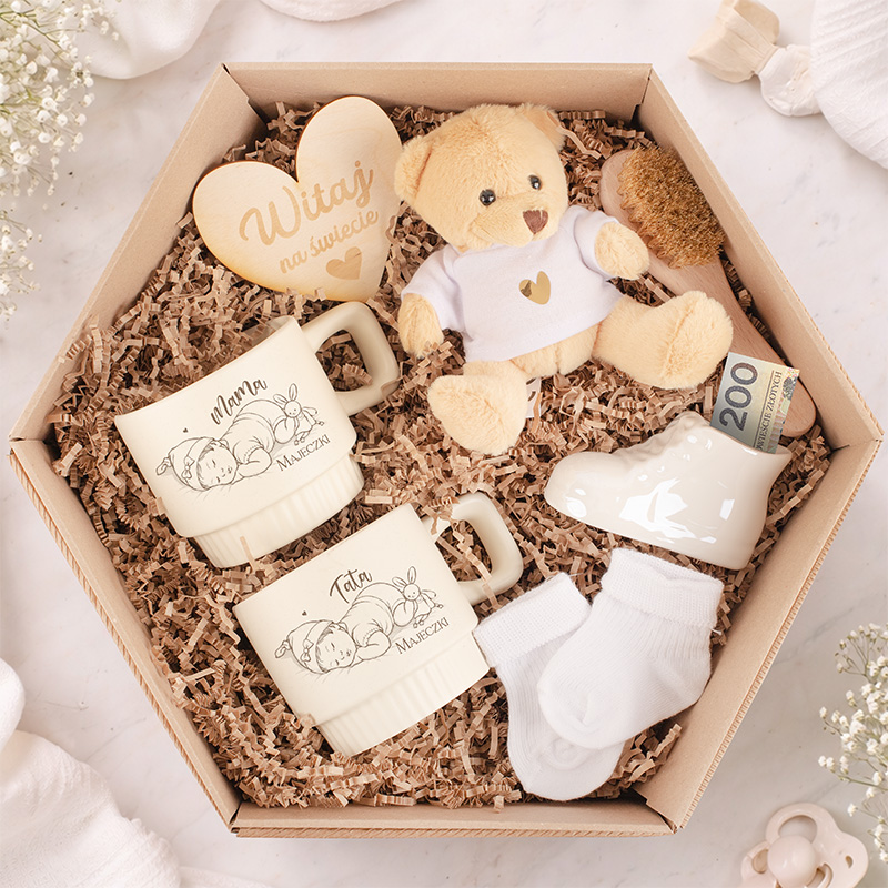 Zestaw prezentowy zawierający dwa kubki z napisami "Mama" i "Tata", małego misia, skarpetki oraz drewniane serce z napisem.