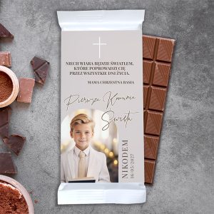 Czekoladki z personalizowaną etykietą, przedstawiającą chłopca w eleganckim ubraniu, z tekstem o pierwszej komunii.