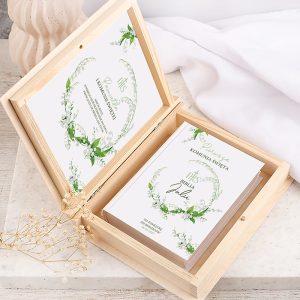 Elegancki zestaw zaproszeń weselnych w drewnianym pudełku, zdobiony delikatnymi kwiatowymi motywami.