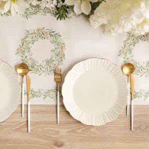 Stół nakryty eleganckim obrusem z roślinnymi wzorami, z talerzami i złotymi sztućcami po obu stronach.