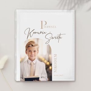 Biała okładka albumu na zdjęcia z napisem "Pierwsza Komunia Święta", z imieniem "Nikodem" i datą "16/05/2027". Na tle uśmiechnięty chłopiec w białej koszuli.