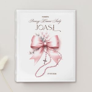 Okładka na pamiątkę z pierwszej komunii, z różową kokardą, kwiatami i różowym różancem, z napisem 'Pamiątka Pierwszej Komunii Świętej JOASI' oraz datą '17/05/2026'.