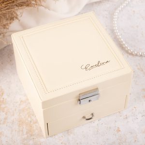 Elegancka, kremowa szkatułka na biżuterię z metalowym zamkiem, na wierzchu podpis "Ewelina".