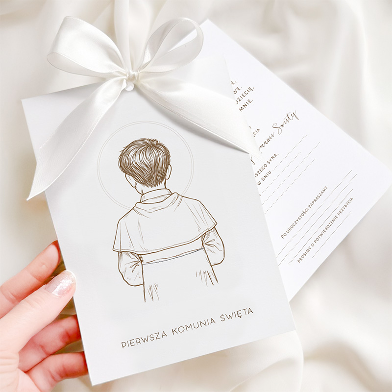 Kartka zaproszeniowa na Pierwszą Komunię Świętą, trzymana w dłoni, z ilustracją tylnej części dziecka w białej szacie, ozdobiona białą wstążką i tekstem w dolnej części z napisem 'PIERWSZA KOMUNIA ŚWIĘTA'.