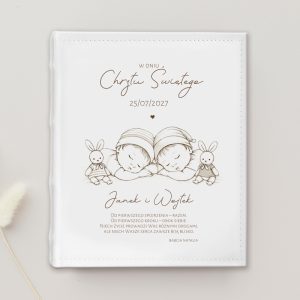 Obszerny album w kolorze białym z delikatnym rysunkiem dwóch małych dzieci śpiących przytulonych obok siebie z królikami.