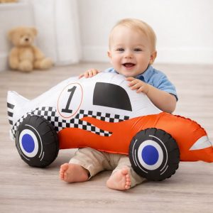 Małe dziecko siedzi na podłodze z dużym balonem w kształcie wyścigowego samochodu.