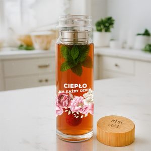 Szklany dzbanek z napojem z owocami i listkami mięty, z napisem "CIEPŁO NA KAŻDY DZIEŃ" oraz drewnianą pokrywką z napisem "MAMA".