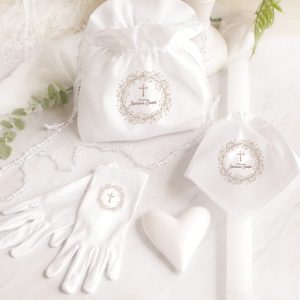 Biała saszetka z metalicznym nadrukiem, jednorazowe rękawiczki, serce i świeca, wszystko w eleganckim otoczeniu.