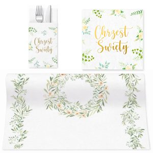 Zestaw dekoracji stołowych z białym podkładem, ozdobiony zielonymi liśćmi i kwiatami; zawiera serwetkę z napisem "Chrzciny" oraz etui na sztućce.