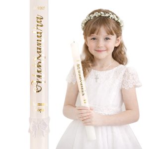 Dziewczynka w białej sukience i z kwiatową opaską na głowie trzyma świecę komunijną z napisem "Pierwsza Komunia Święta".