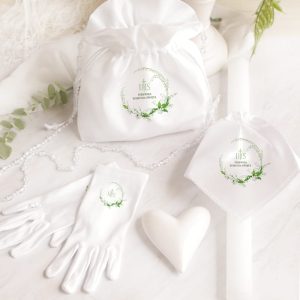 Białe akcesoria ze zdobieniami, w tym torba, chusteczka, rękawiczki i świeca, ułożone na jasnym tle.