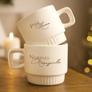 Dwie białe filiżanki, jedna na drugiej, z eleganckim imieniem i "Najlepsza Nauczycielka".