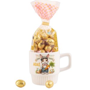 kubek-z-zajaczkiem-i-jajkami-upominek-na-wielkanoc.jpg Filiżanka z rysunkiem królika, wypełniona czekoladowymi jajkami w złotym opakowaniu.
