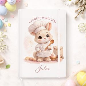Zeszyt z ilustracją uroczej królika w kucharskim fartuchu, trzymającego łyżkę, otoczony ciastkami i dekoracjami.