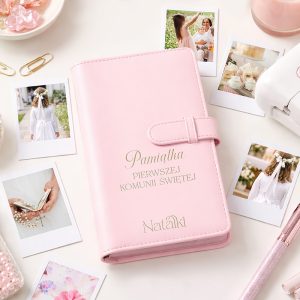 Różowy album na zdjęcia z napisem "Pamiątka Pierwszej Komunii Świętej" i imieniem "Natalka", otoczony kolorowymi dekoracjami.