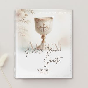 Białe album z eleganckim kielichem na okładce, ozdobiony kwiatuszkami i napisem "Album Pierwsza Komunia Święta".