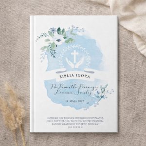 prezent-na-pierwsza-komunie-dla-chlopca.jpg Okładka Biblii z subtelnym niebieskim tłem, białym tekstem i delikatnymi kwiatowymi akcentami, zawierająca datę i dedykację.
