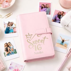 Różowy notes z napisem "Sweet 16" i koroną, otoczony zdjęciami w pastelowych kolorach, ozdobami i przyborami biurowymi.