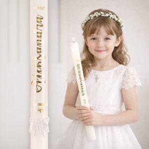 Dziewczynka w białej sukience z koronkowymi rękawami trzyma świecę na Komunię, z napisem "Pierwsza Komunia Święta".